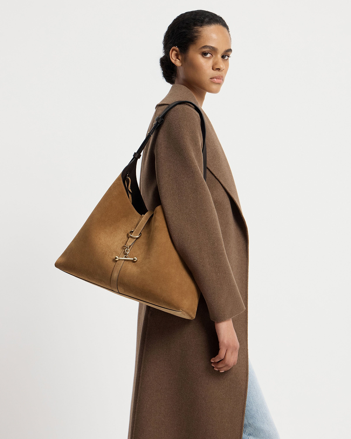 Model wearing brown coat carrying toffee suede hobo bag with espresso strap.