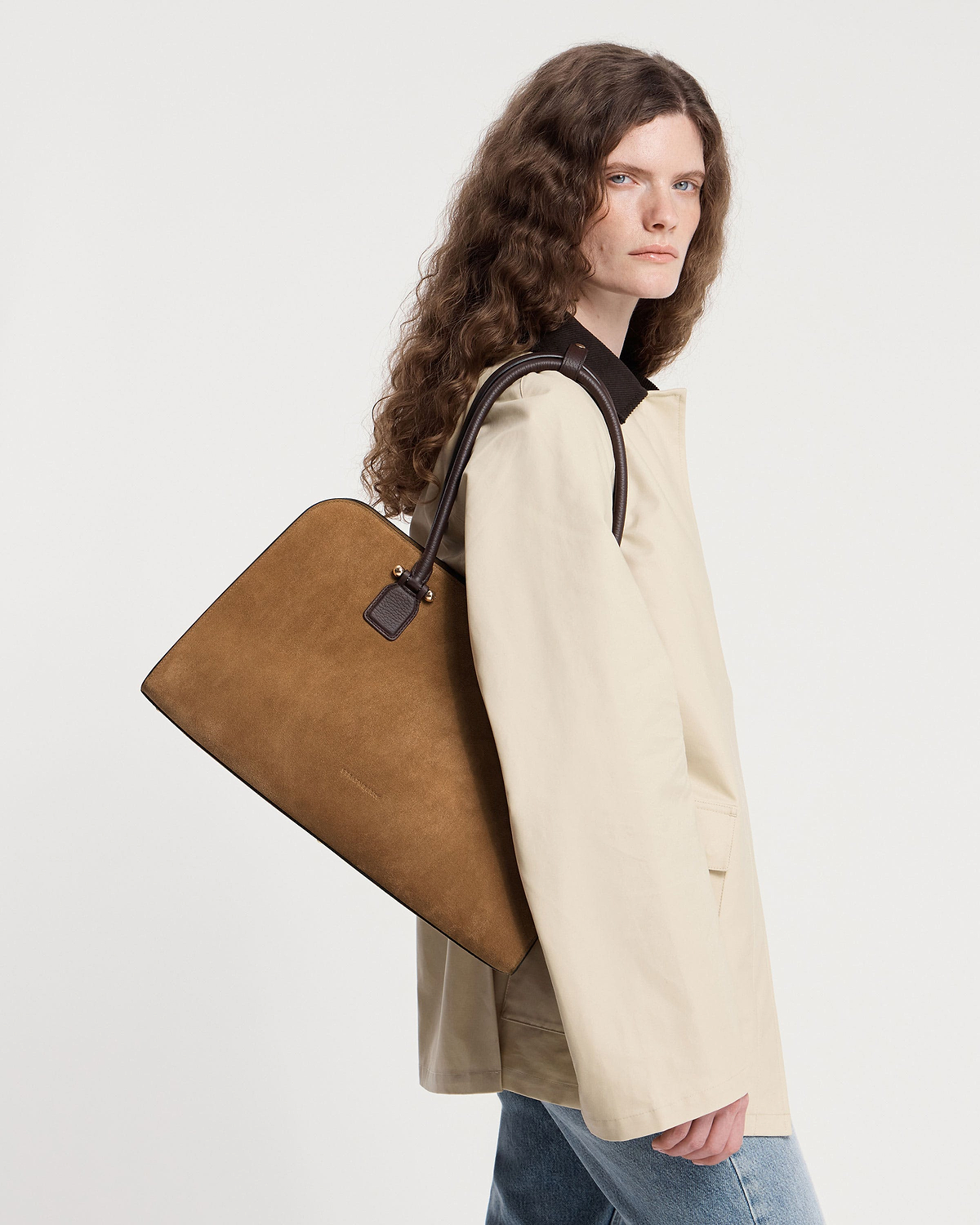 Model carrying a toffee suede and espresso leather tote over her shoulder.