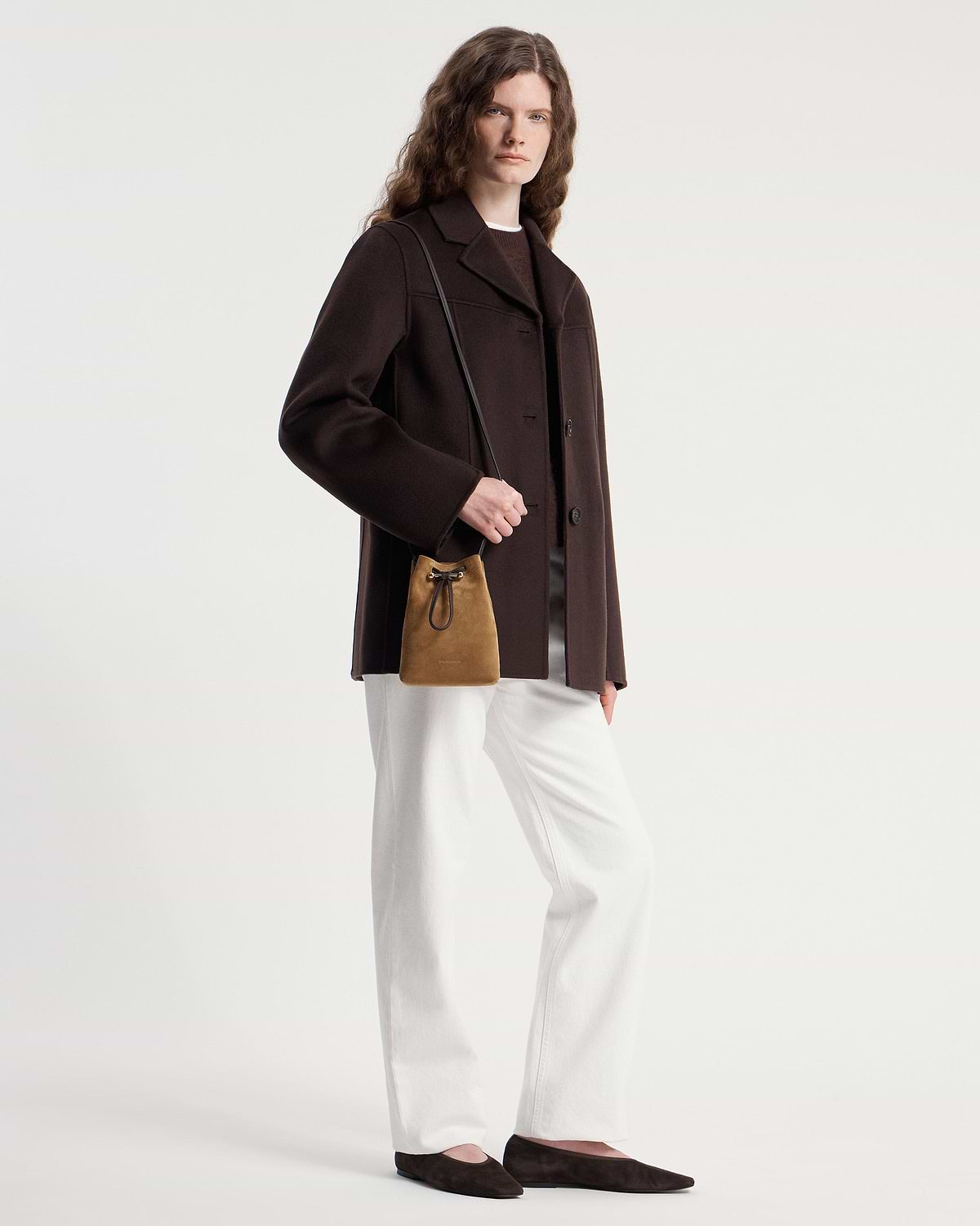Model wearing a toffee suede drawstring midi pouch with espresso shoulder strap.