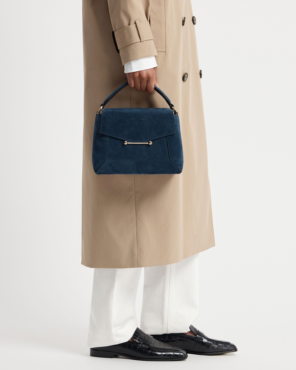 Loch blue suede mosaic bag with top handle, held against a beige coat.