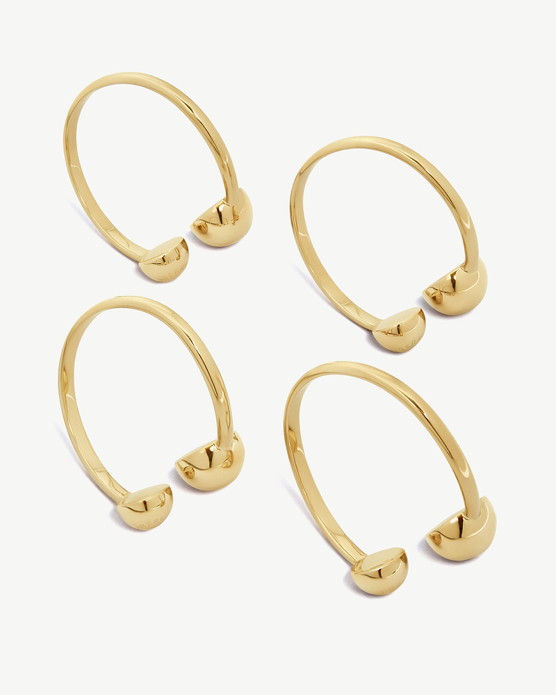 Multiple light gold napkin holders with rounded end caps on white background.