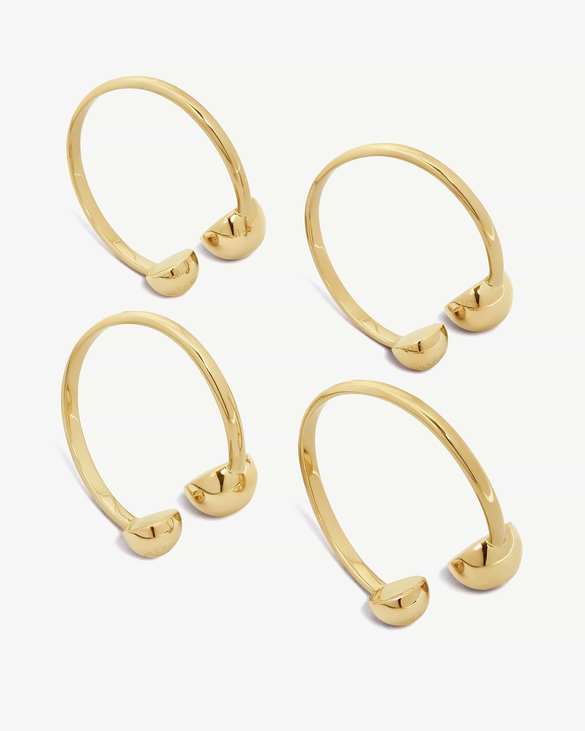 Multiple light gold napkin holders with rounded end caps on white background.
