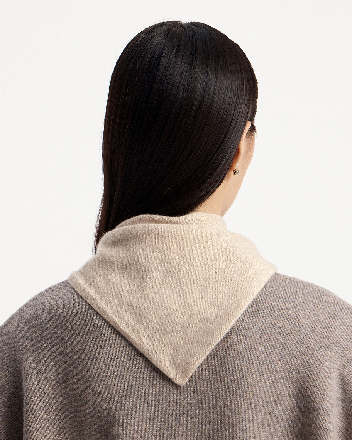 Back view of a model wearing an oat cashmere bandana draped over shoulders.
