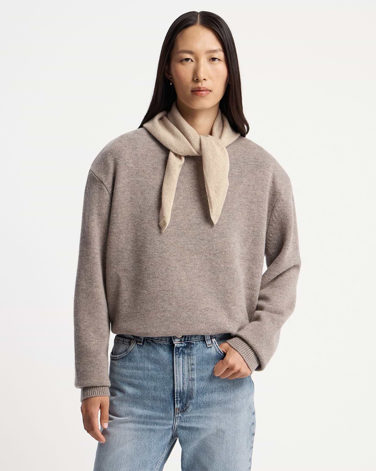 Model wearing an oat cashmere bandana tied at the neck and grey sweater.