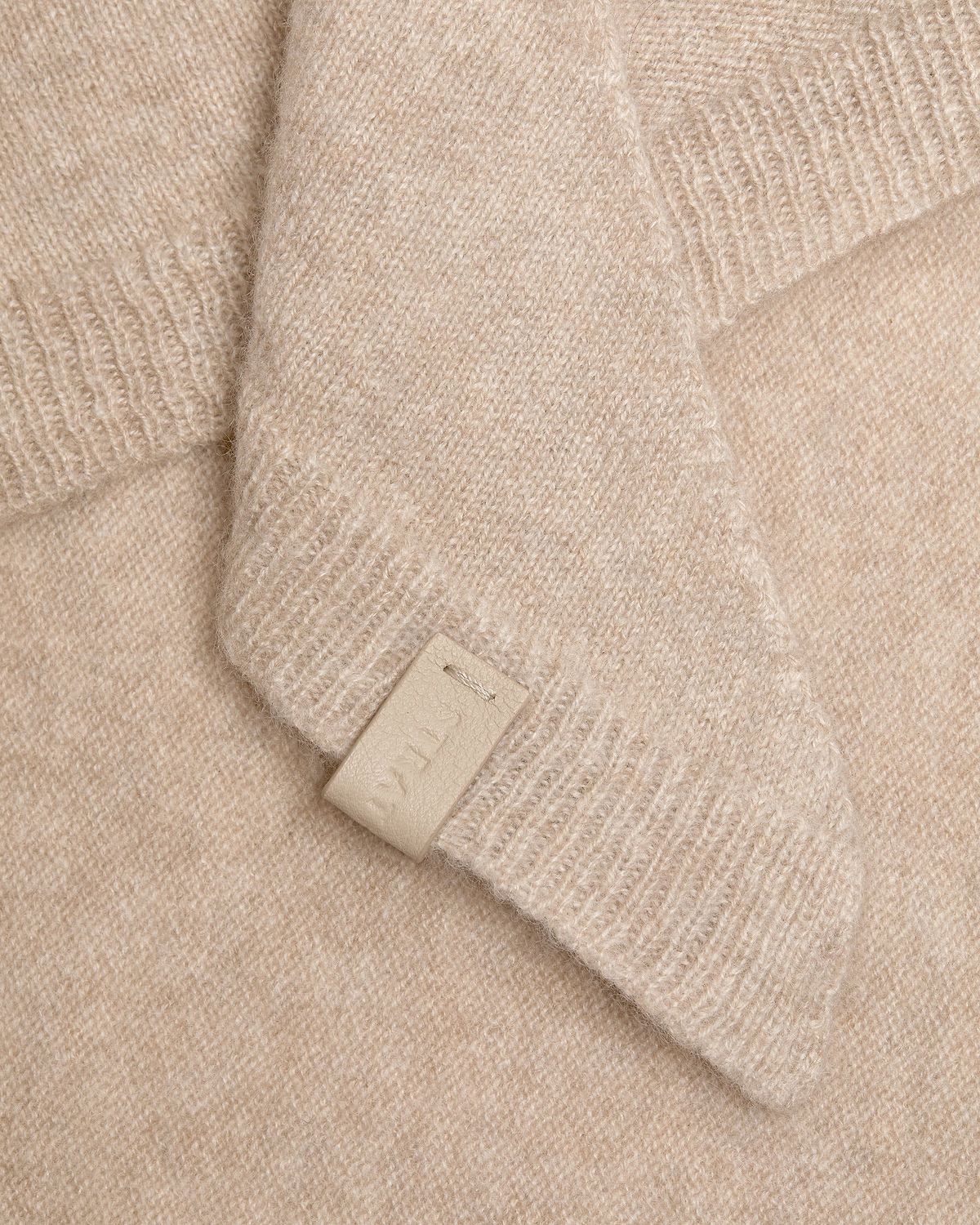 Oat-coloured cashmere bandana with visible knit texture and a small leather tag.
