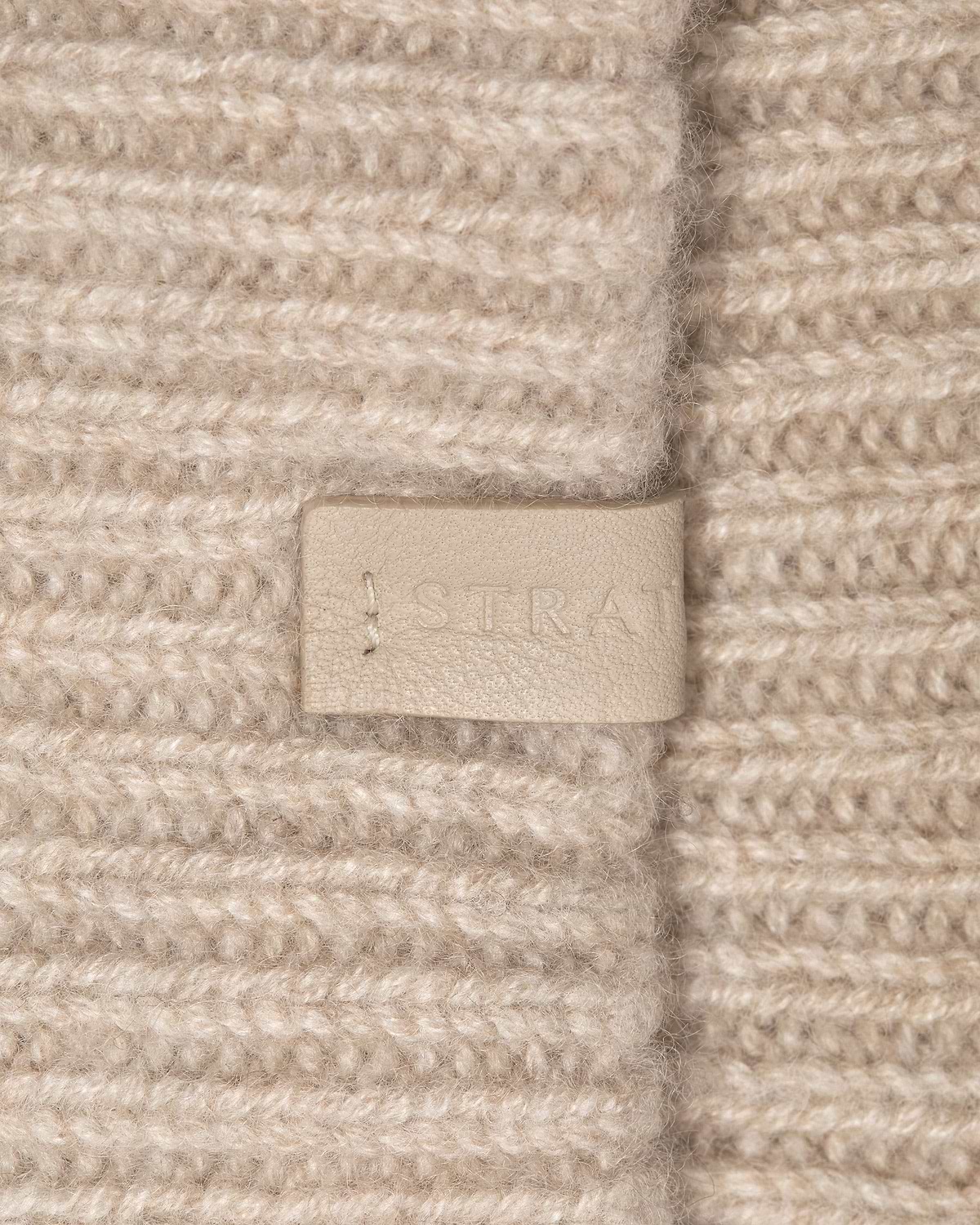 Ribbed oat cashmere headband with leather Strathberry logo tag and visible stitching.