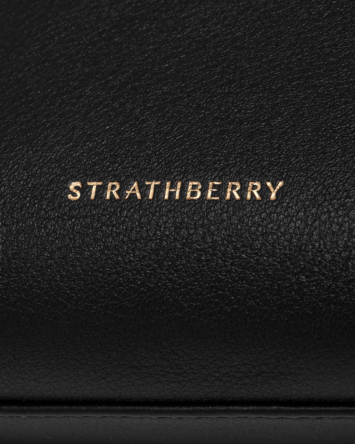 Black pebbled leather pouch with gold Strathberry logo on front.