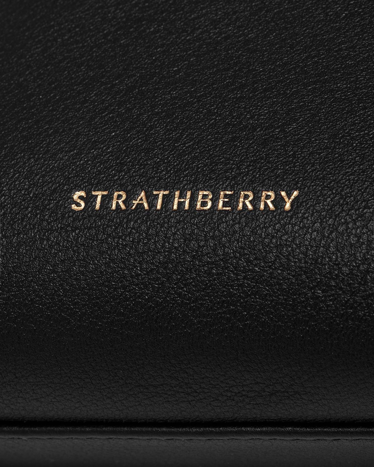 Black pebbled leather pouch with gold Strathberry logo on front.