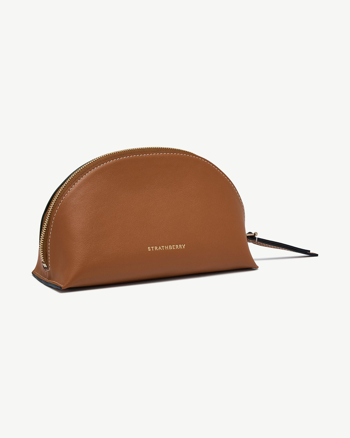 Tan Strathberry Nest pouch with gold logo and zip, leather surface visible.