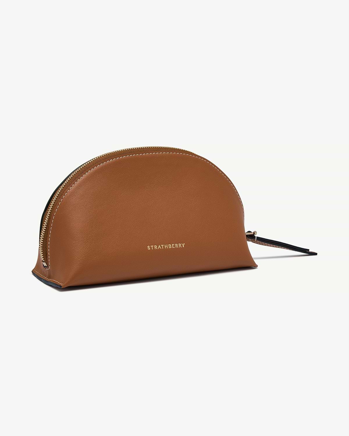 Tan Strathberry Nest pouch with gold logo and zip, leather surface visible.