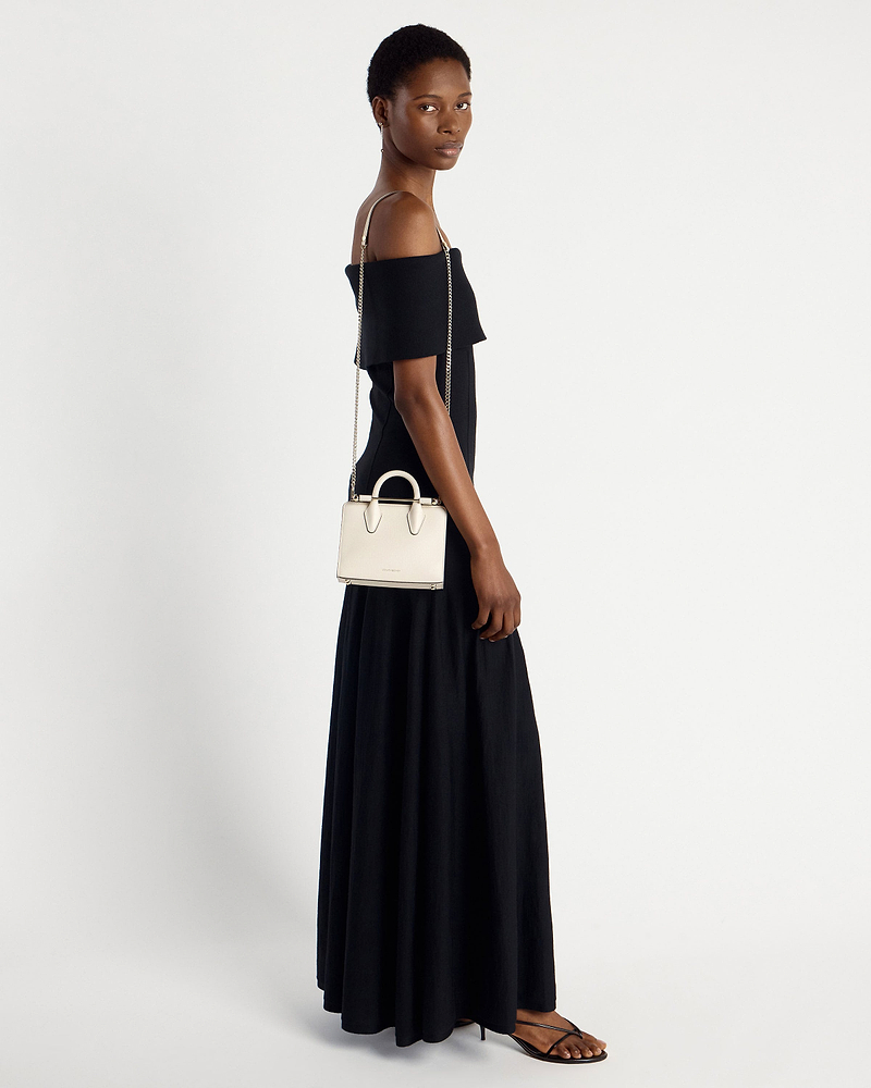 Model wearing black off-shoulder dress with vanilla nano tote on chain strap.