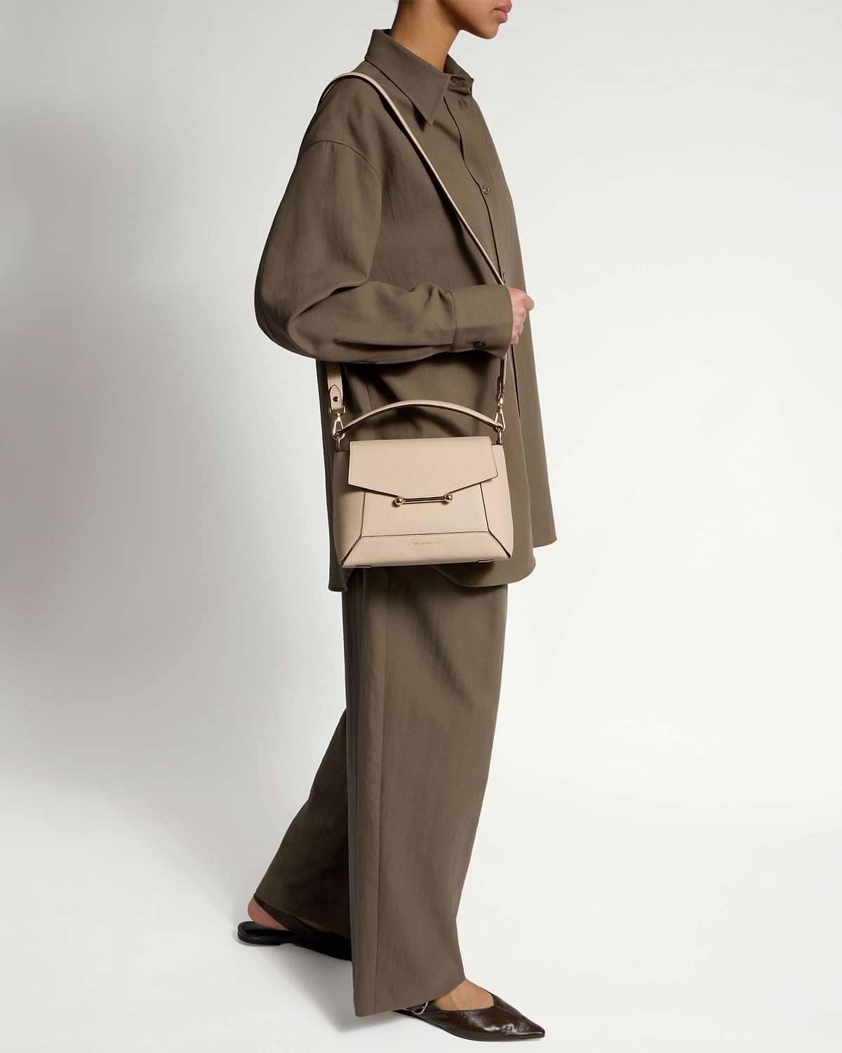Model wearing oat-coloured mosaic bag across body with oversized brown shirt and wide trousers.