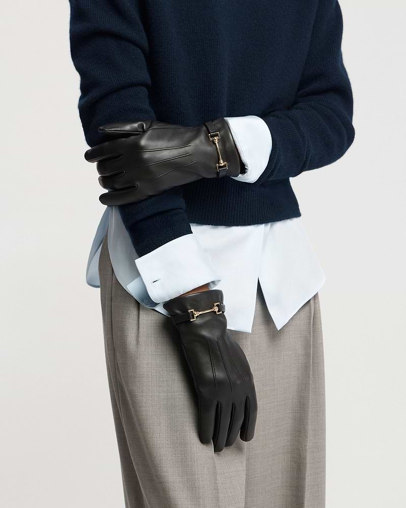 Black leather gloves with gold horsebit detail worn with navy jumper and shirt.