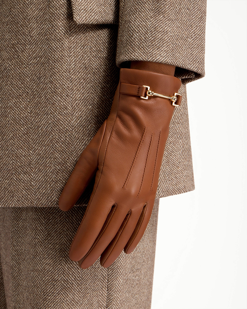 Tan leather gloves with gold bit detail worn with herringbone coat.