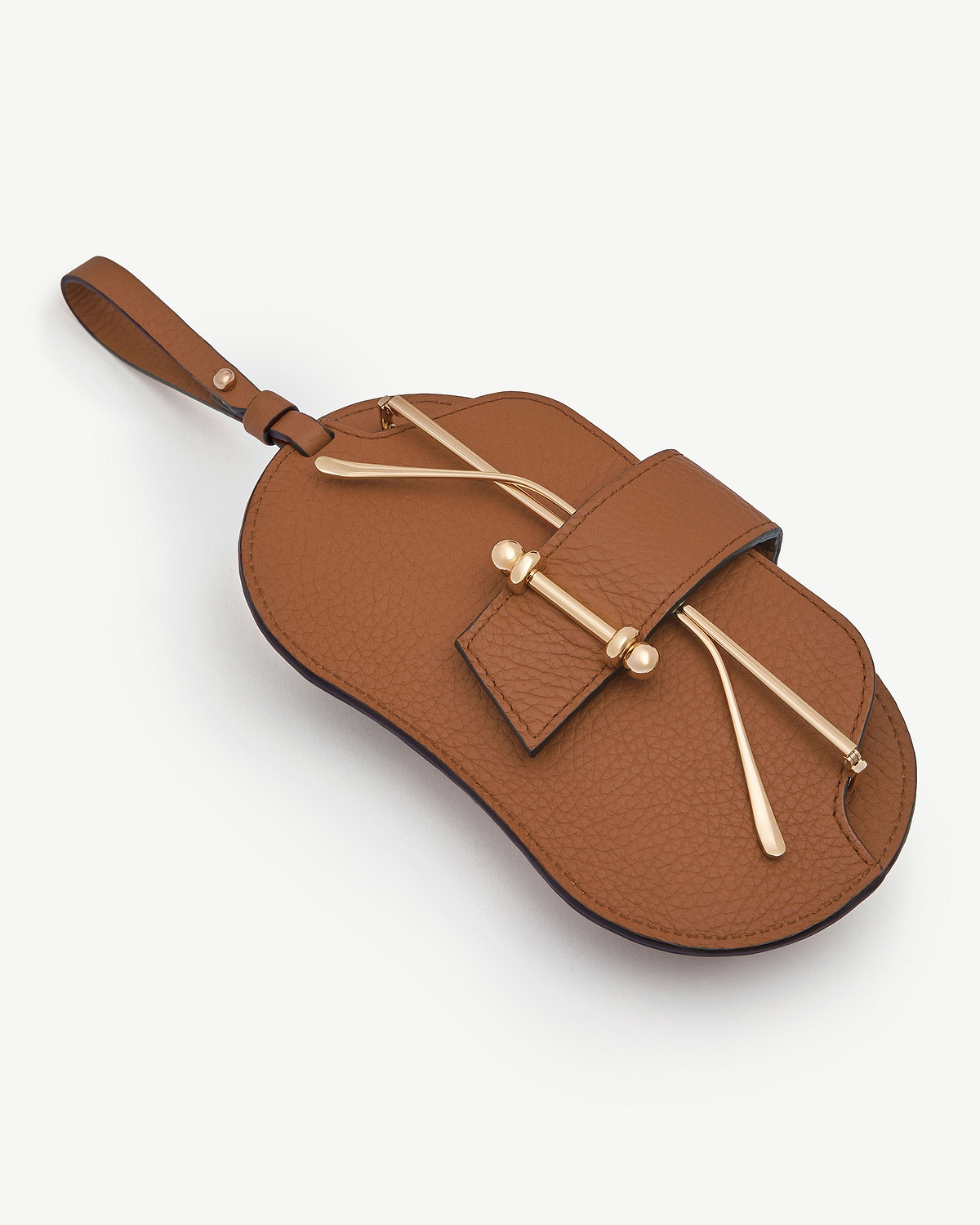 Tan pebbled leather sunglasses case with wrist strap and gold-tone bar detail.