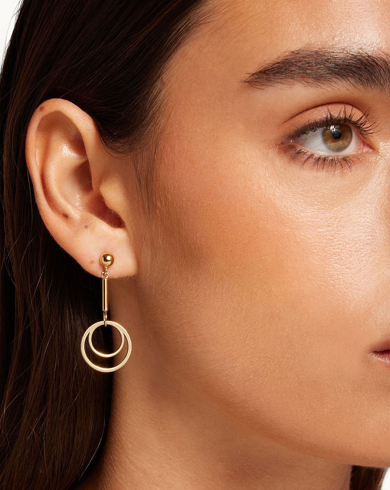 Left ear with 22 carat gold-gilded circle drop earring, partial face visible
