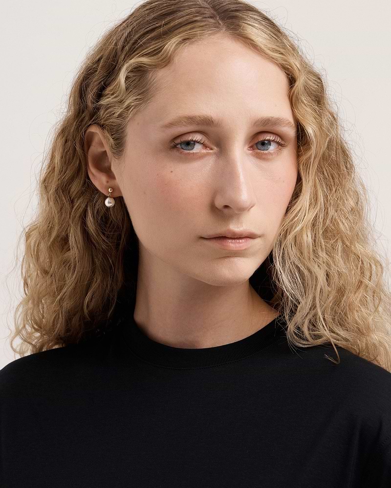 Model wearing 24-carat gold gilded pearl drop earrings, head and shoulders visible.