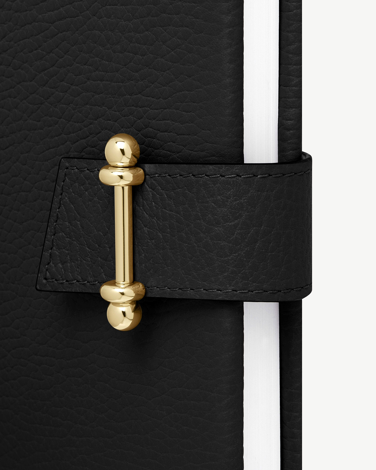 Black leather notebook with gold bar clasp and white page edges.