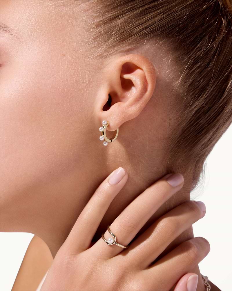 22 carat gold gilded pearl huggie and matching pearl ring on model's ear and finger