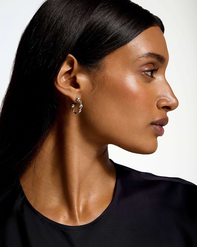 Woman in profile wearing sterling silver crescent twisted hoop earring.