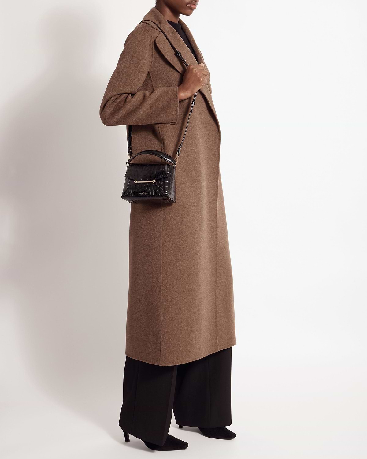Model in brown coat carrying a soft croc Mosaic Nano crossbody bag.
