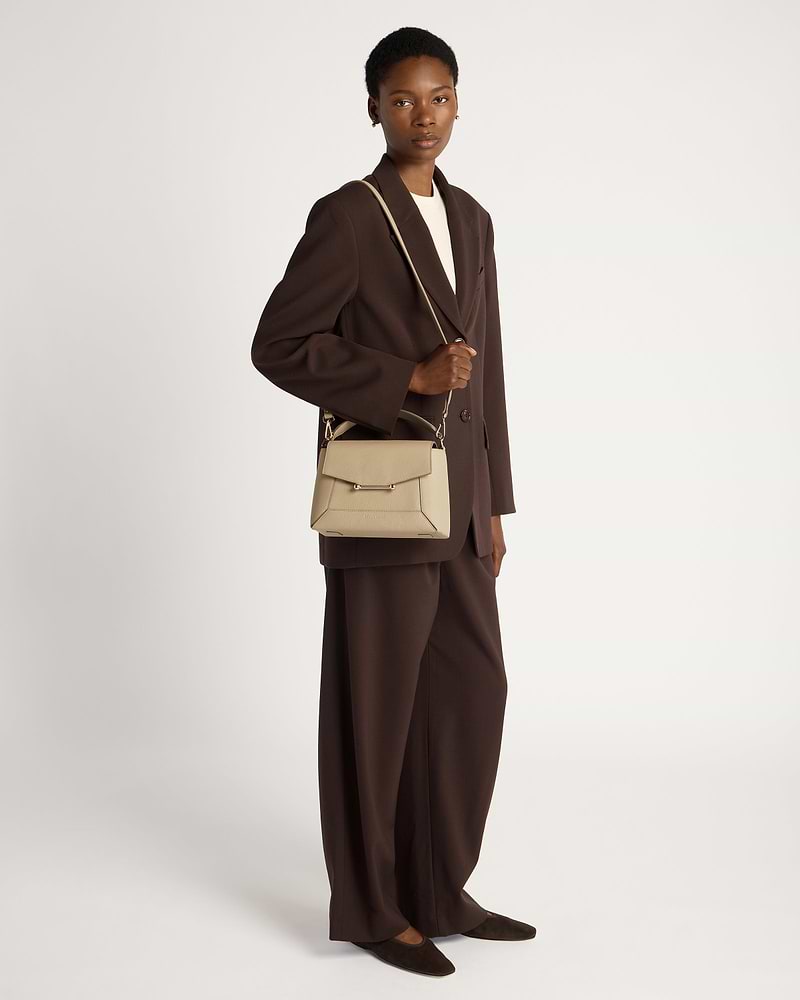 Model wearing a brown blazer holding a sand mosaic bag by shoulder strap.