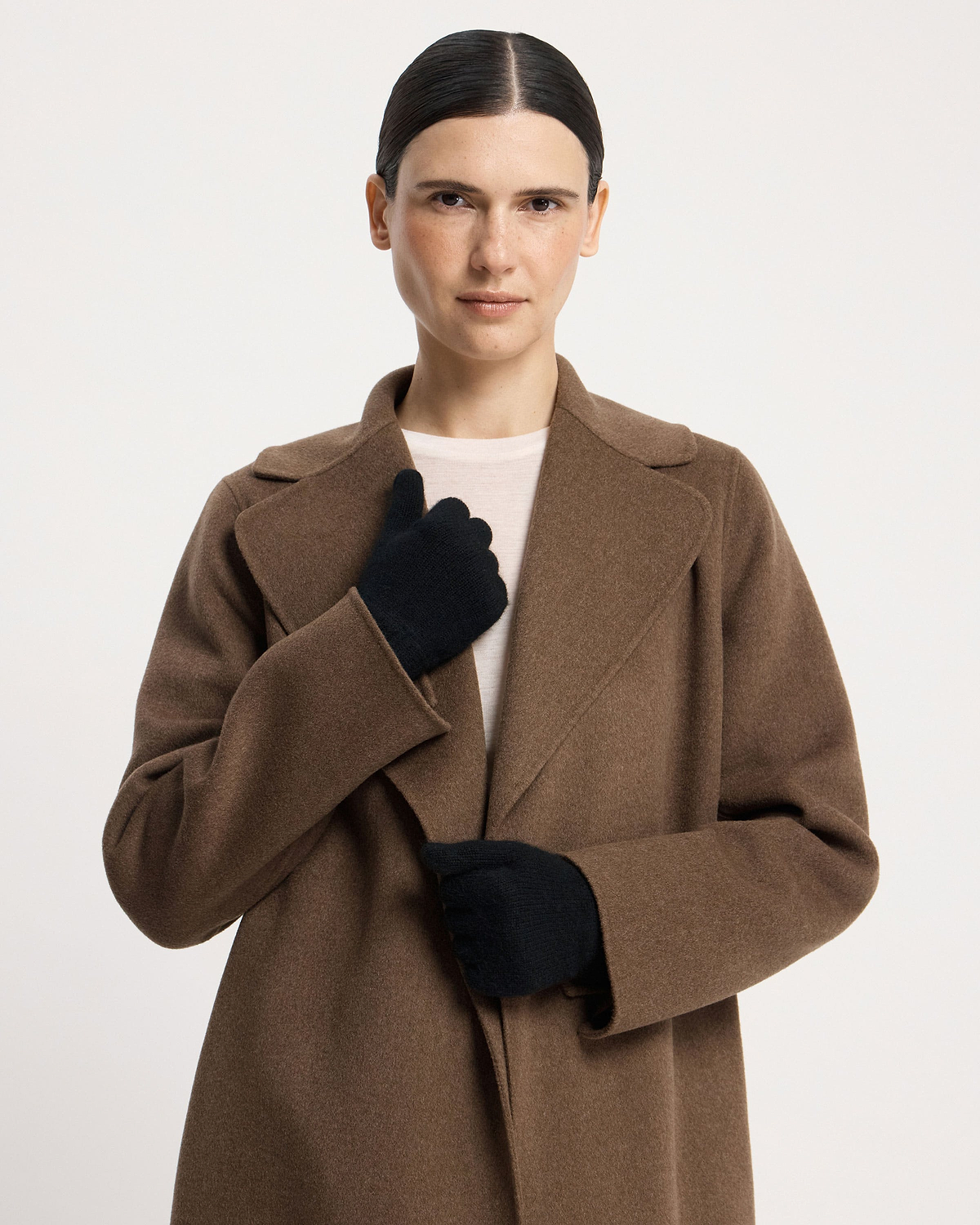 Model wearing black cashmere gloves and brown coat, facing camera.