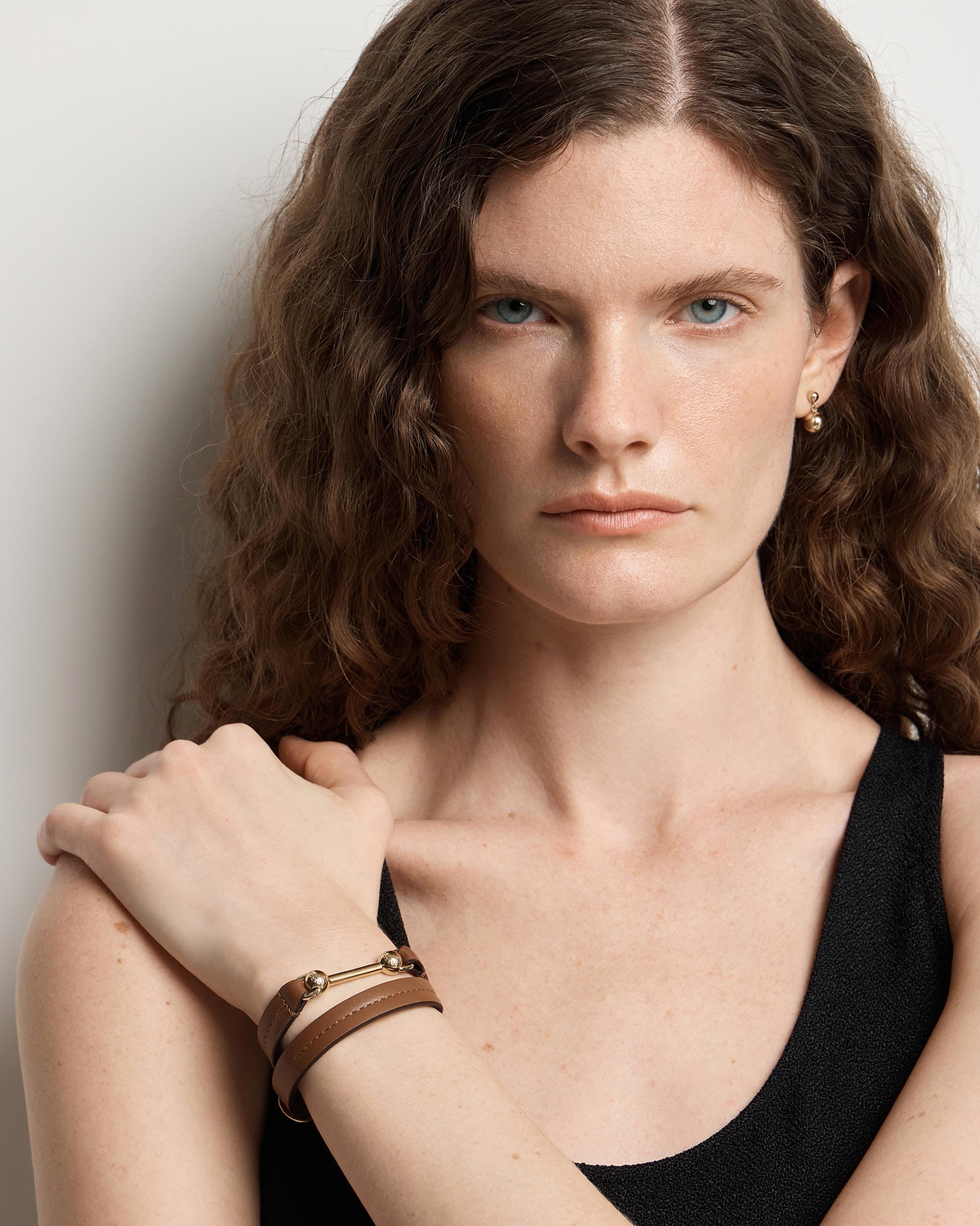 Model wearing hazelnut double-wrap leather bracelet with gold bar hardware on wrist.