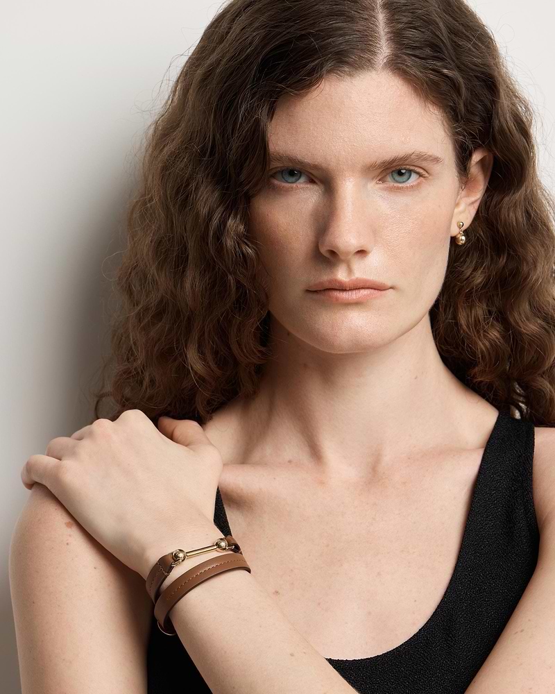 Model wearing hazelnut double-wrap leather bracelet with gold bar hardware on wrist.