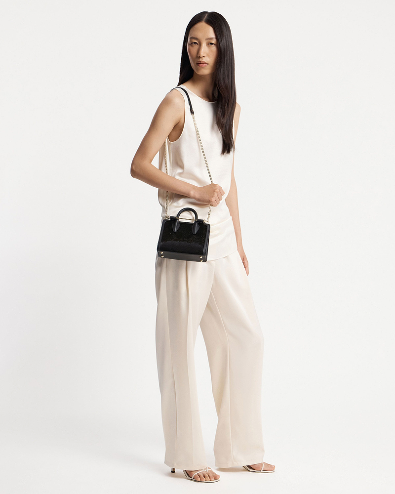Model wearing ivory outfit holding a black sequined nano tote with chain strap