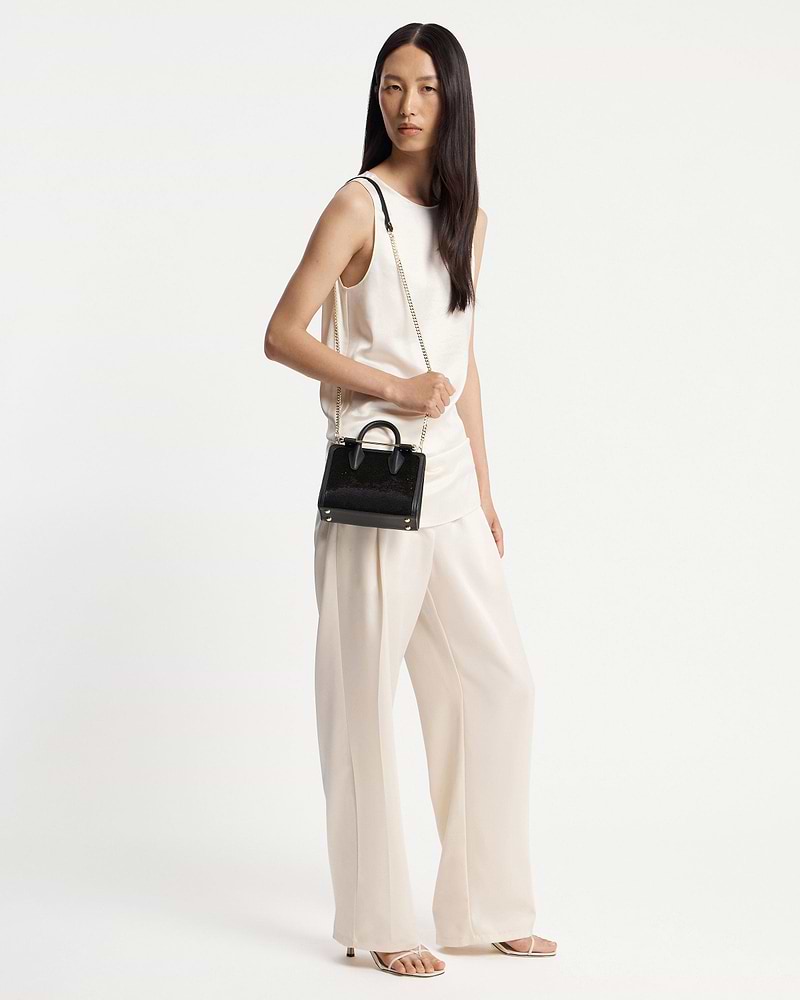 Model wearing ivory outfit holding a black sequined nano tote with chain strap