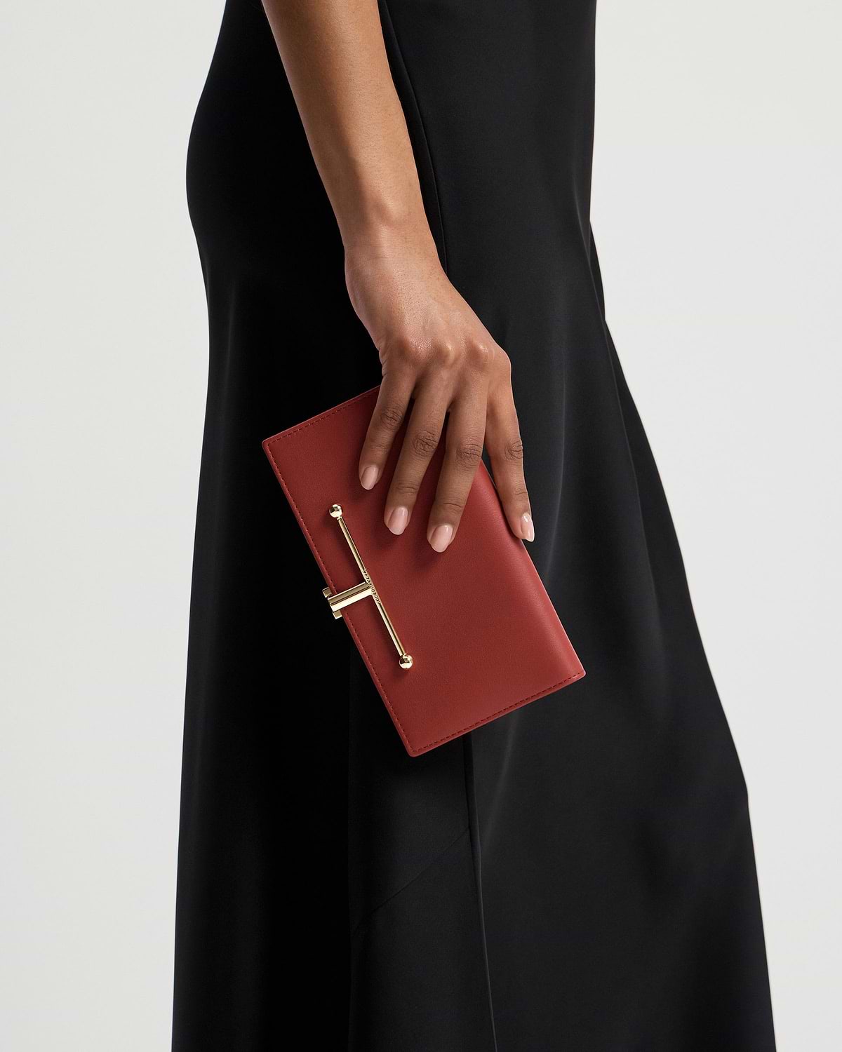 Hand holding Levanto red large Melville Street wallet with gold bar hardware.
