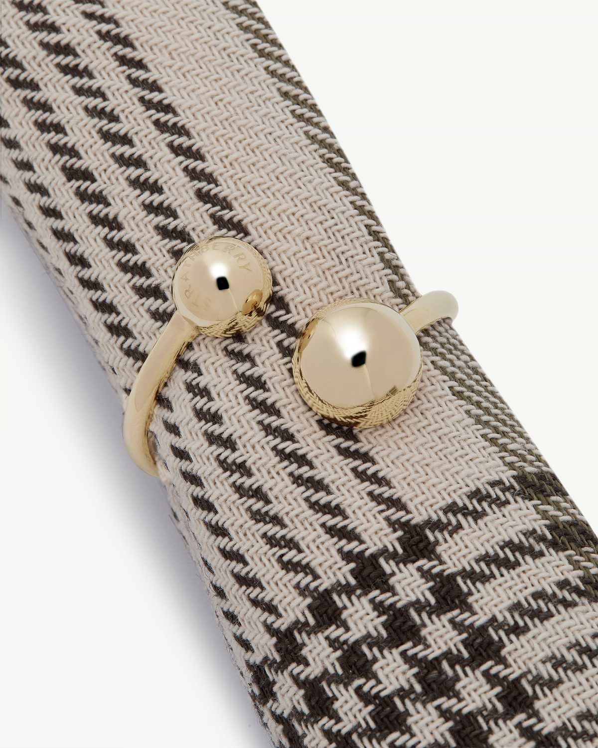 Woven napkin holder with light gold round clasp stamped Strathberry.