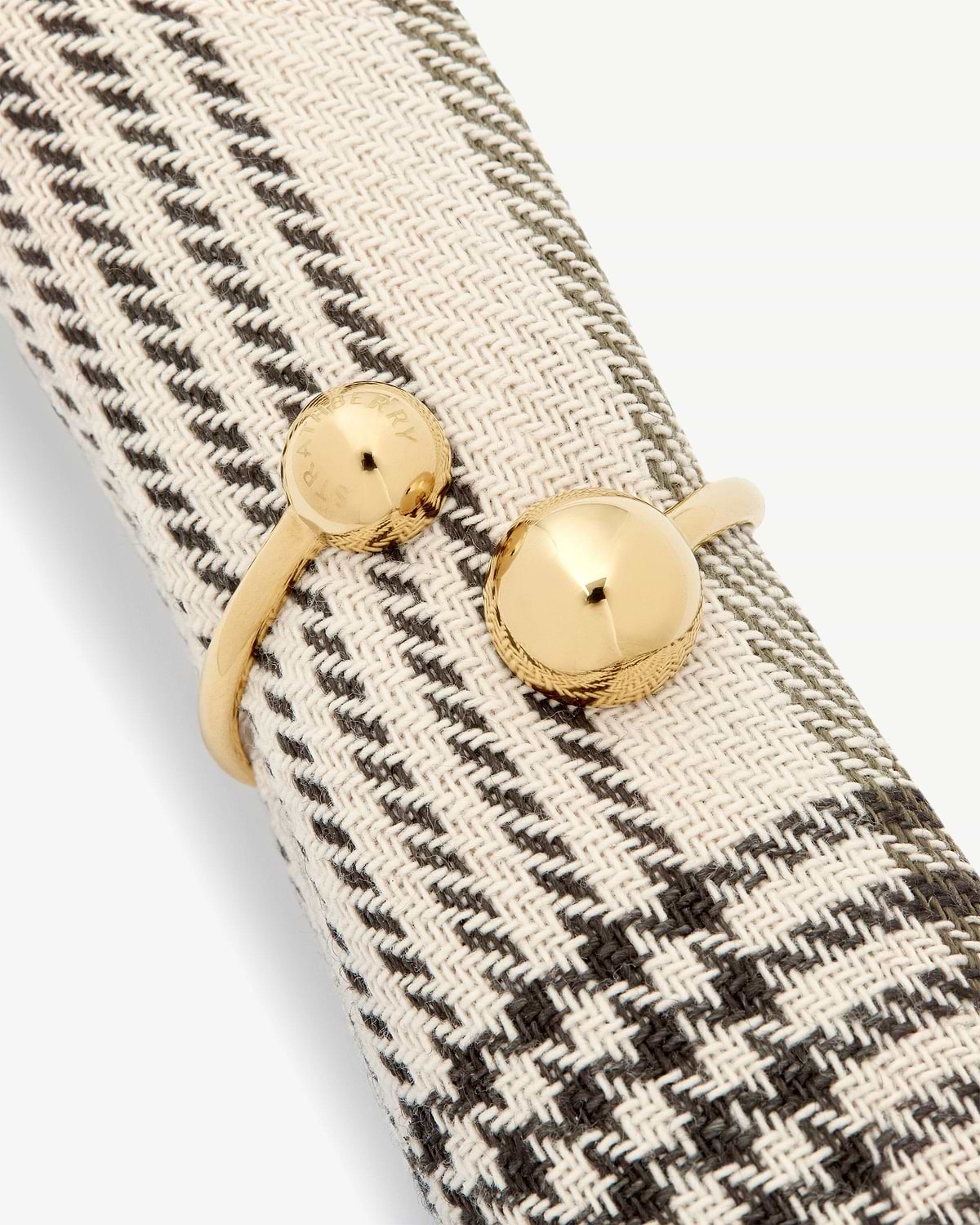 Woven beige herringbone fabric with light gold metal buttons engraved 'Strathberry'.