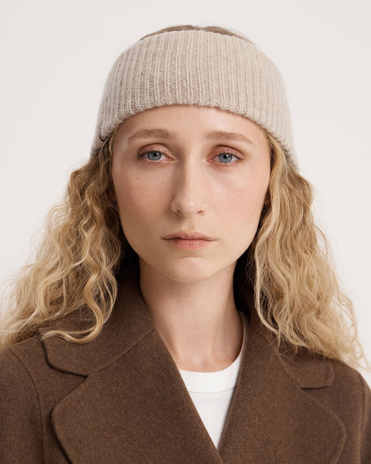 Model wearing ribbed oat cashmere headband, close-up of face and shoulders.