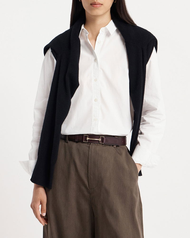 Model wearing burgundy leather belt with gold horsebit buckle, white shirt and brown trousers
