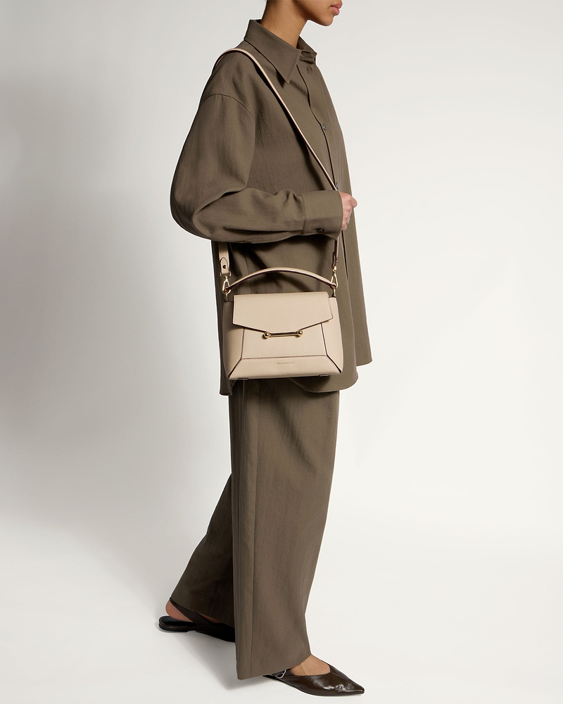 Model wearing oat-coloured mosaic bag with top handle and gold hardware, crossbody.