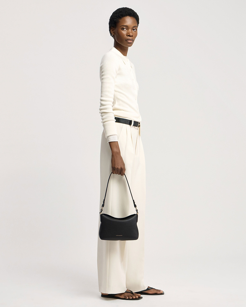 Model holding black Strathberry Sway shoulder bag at her side