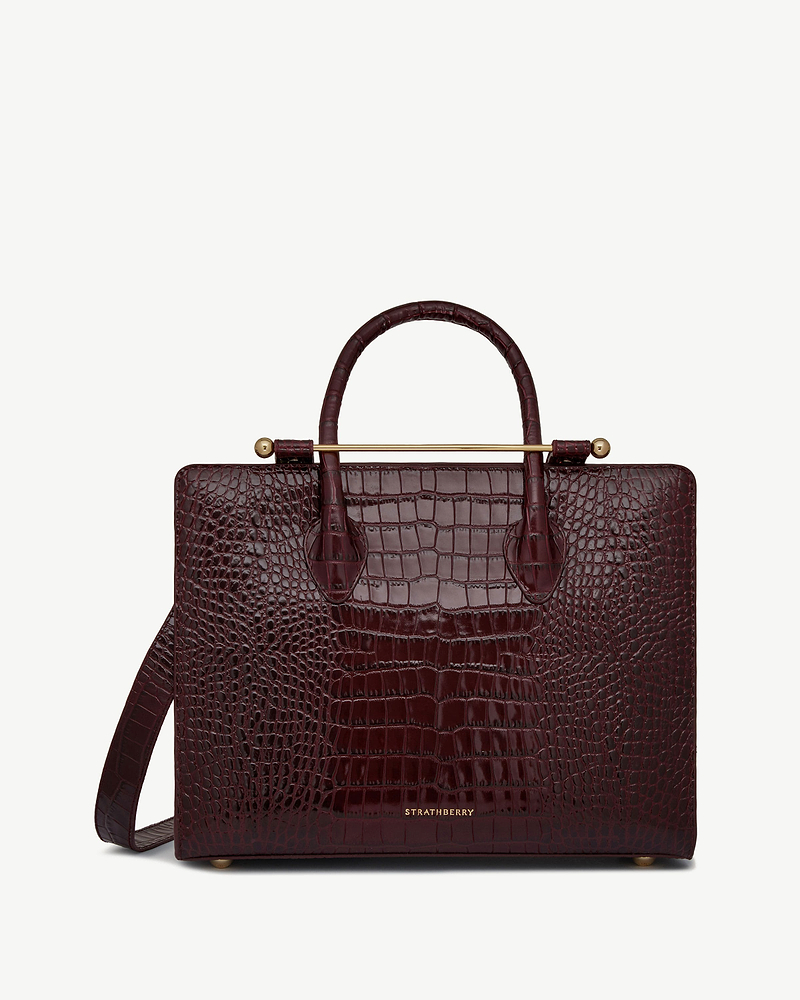 Burgundy croc-embossed leather midi tote with top handles, shoulder strap and Strathberry logo.