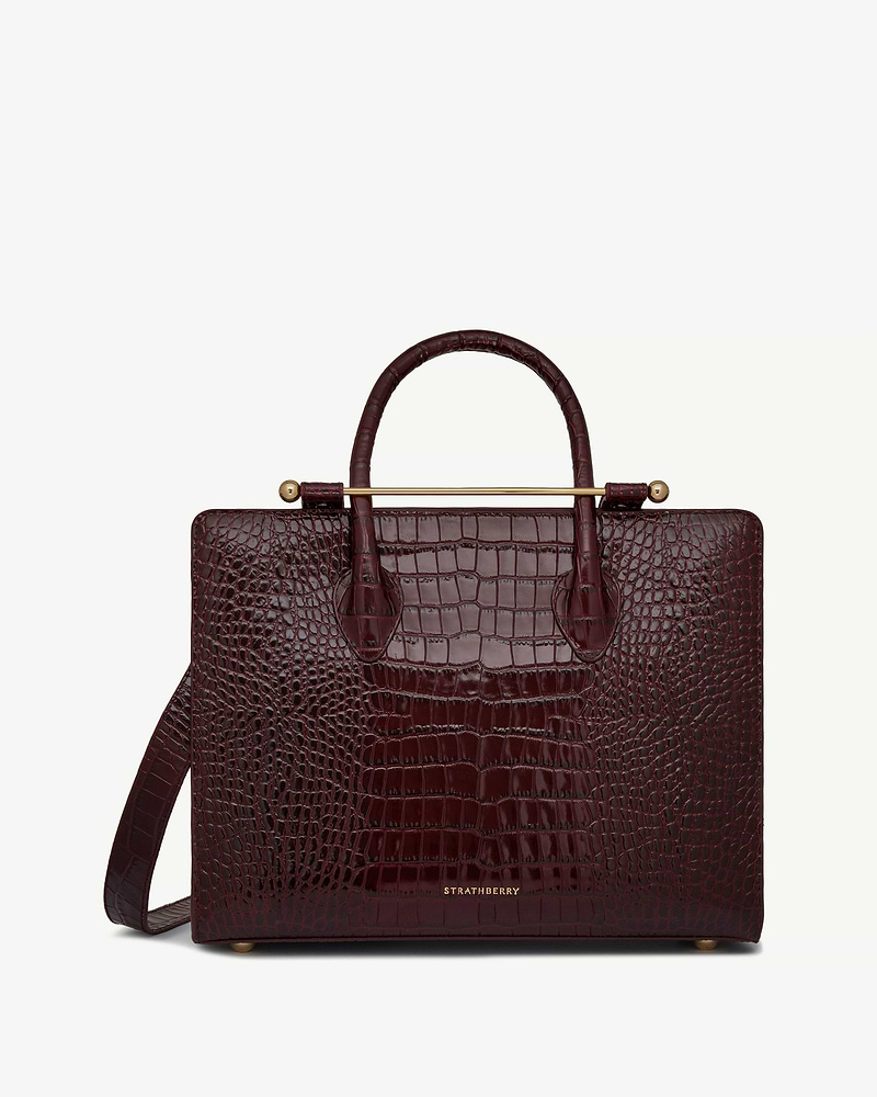 Burgundy croc-embossed leather midi tote with top handles, shoulder strap and Strathberry logo.