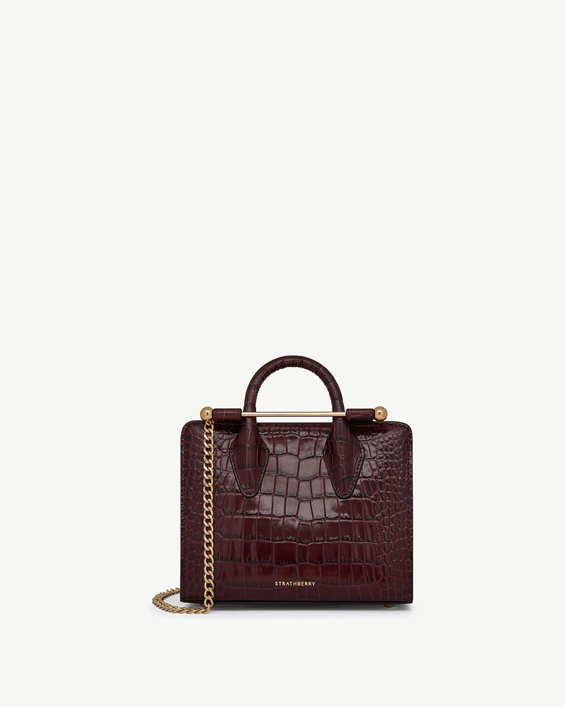 Burgundy croc leather Strathberry nano tote with top handles and gold chain strap.