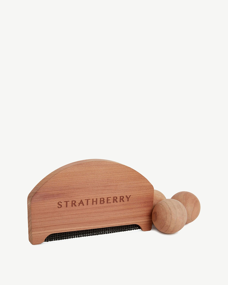 Strathberry cedar lint brush with black fabric strip and three wooden balls.