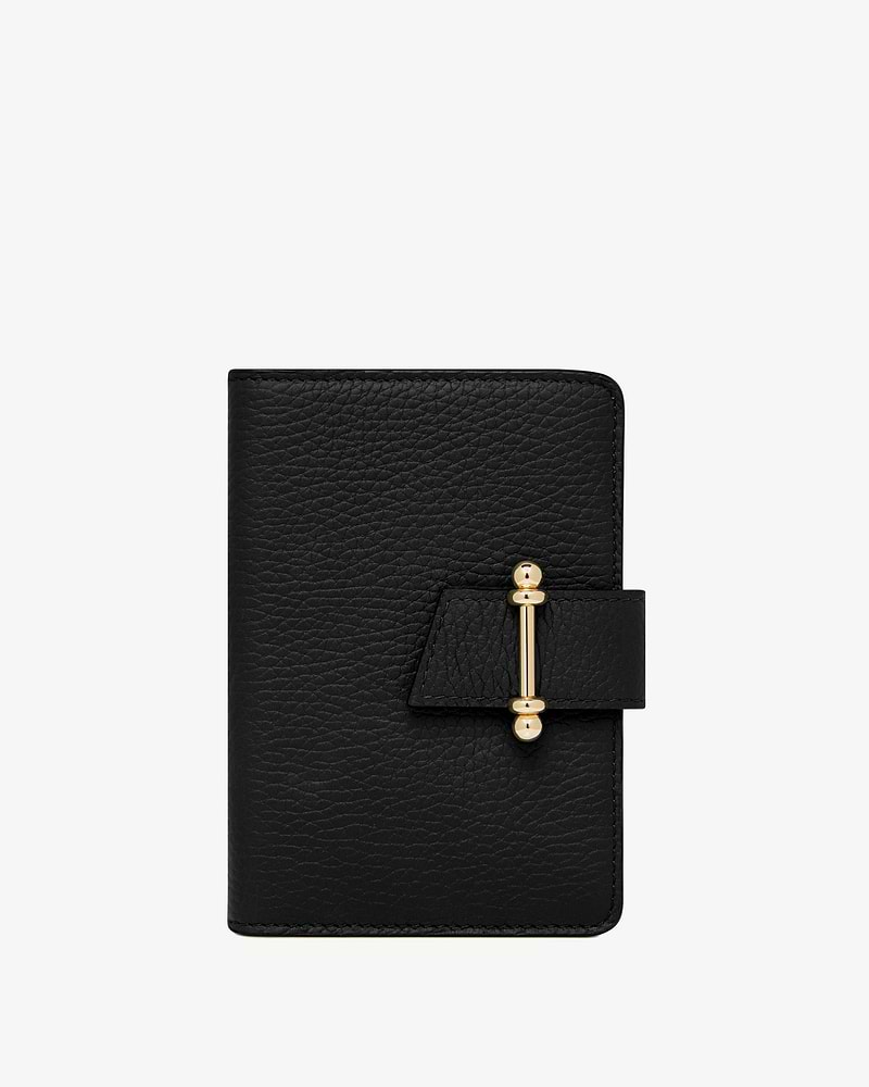 Black grained leather passport holder with gold bar clasp on front strap.
