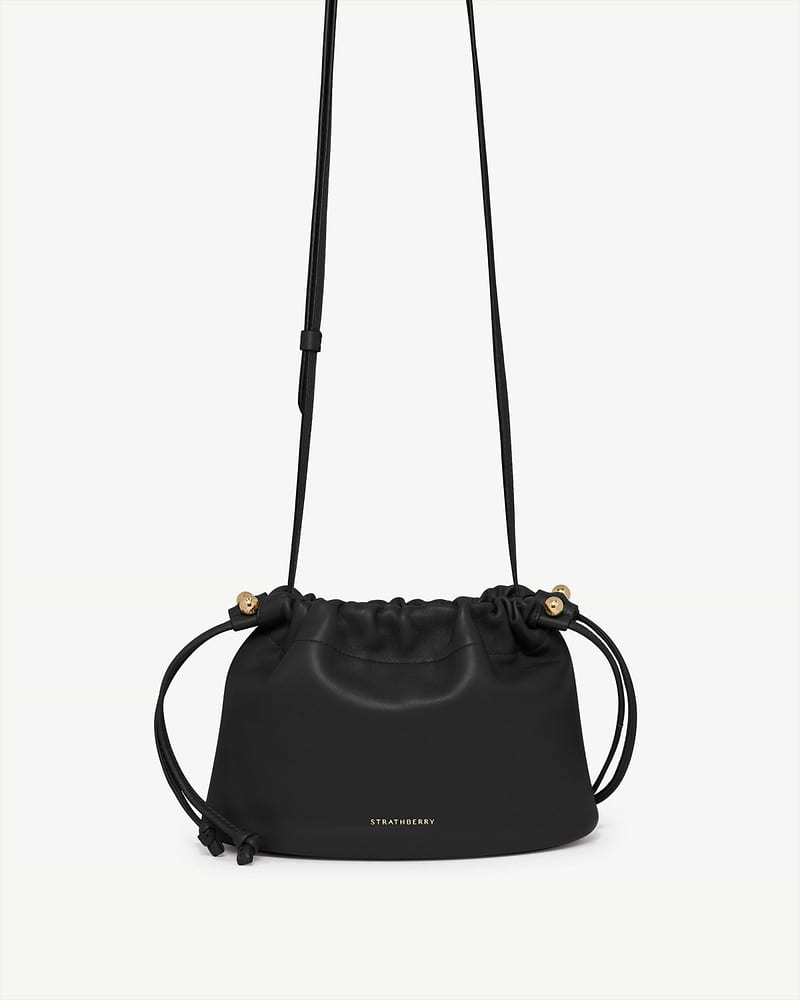 Black Charlotte drawstring bag with gold Strathberry logo and thin strap