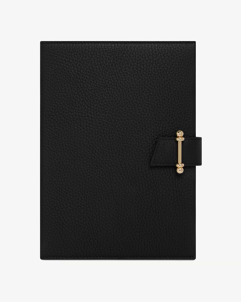 Black leather notebook with textured cover and gold clasp closure, centred on white background.