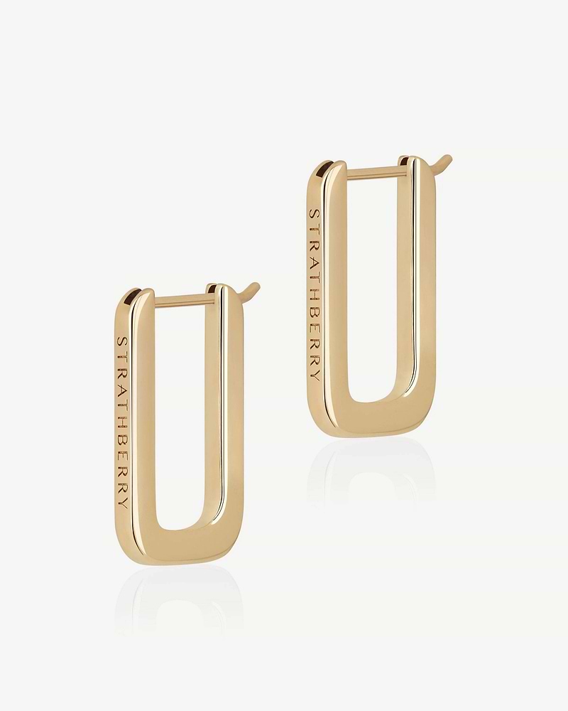 Pair of 22 carat gold rectangular hoop earrings engraved with Strathberry on white background