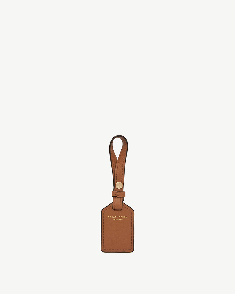 Tan leather rectangular tag with Strathberry logo and looped strap.