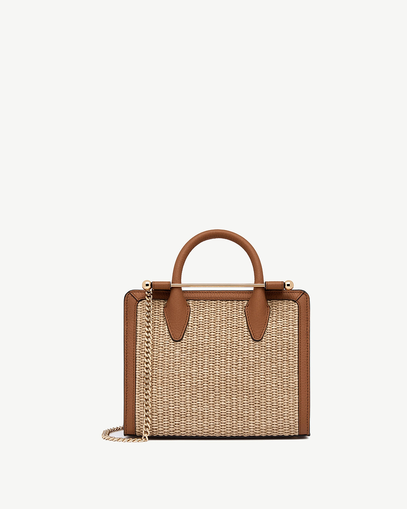 Mini tote with natural raffia body, tan leather trim and gold chain strap.