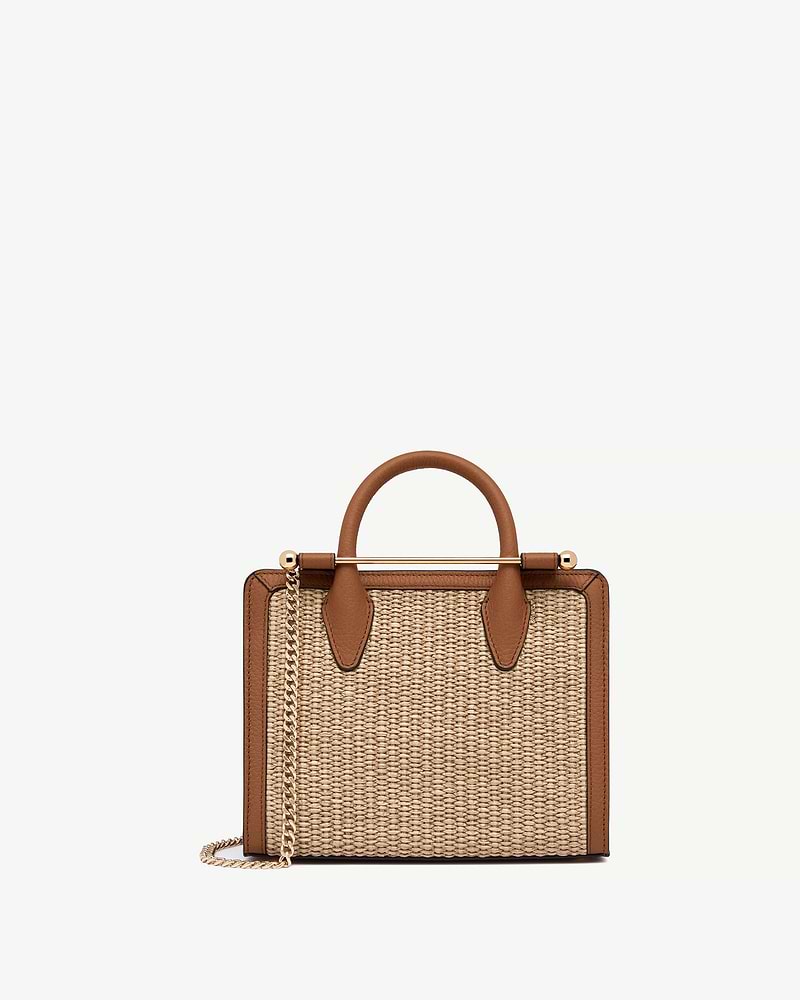 Mini tote with natural raffia body, tan leather trim and gold chain strap.