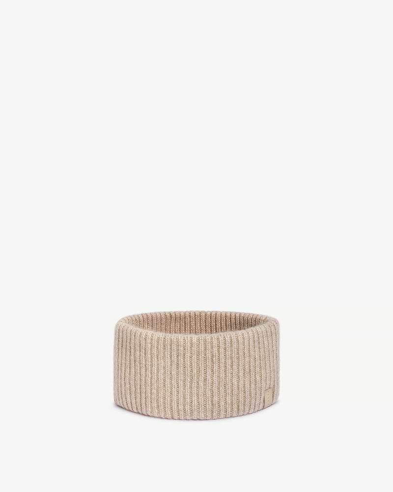 Oat ribbed cashmere headband folded upright with small leather tag on white background.